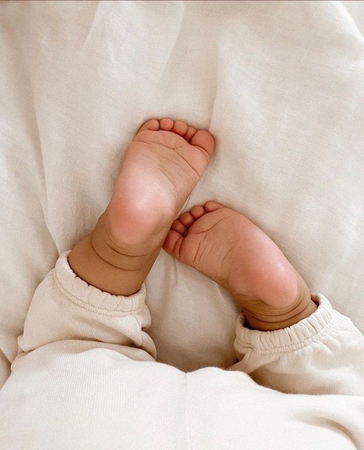 Baby's feet resting on soft white linen